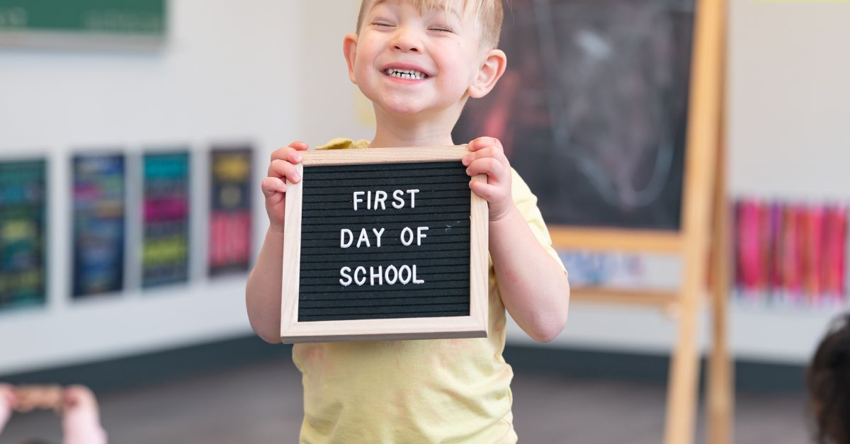 Preschool boy holding up a first day of school sign. 