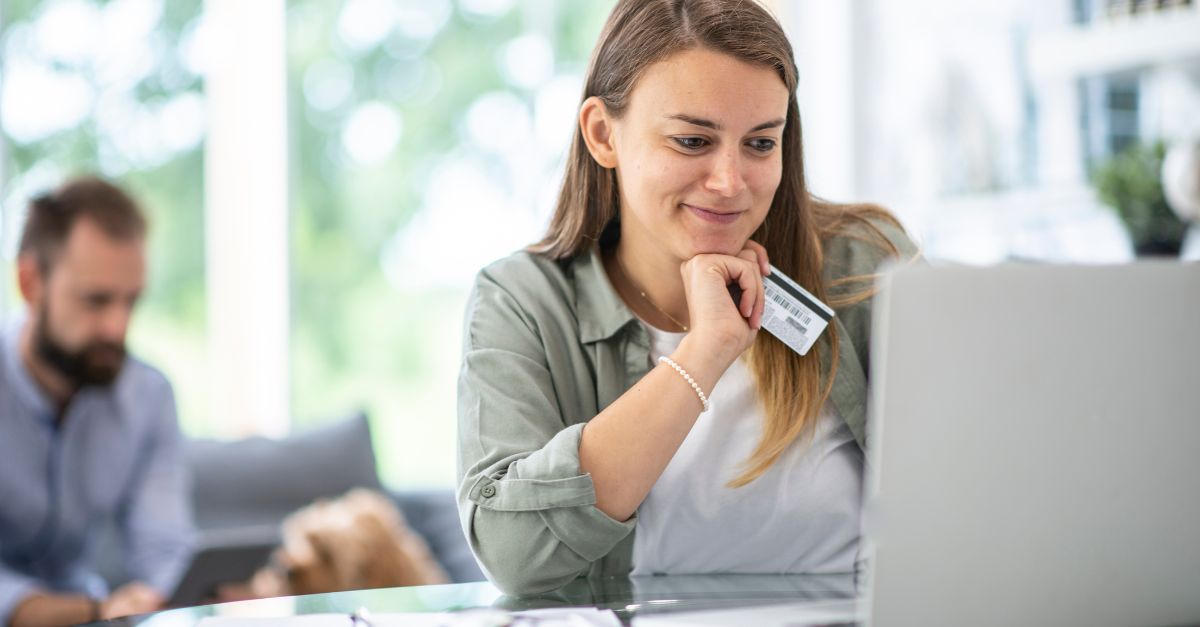 Parent smiling and holding credit card while they pay childcare tuition online