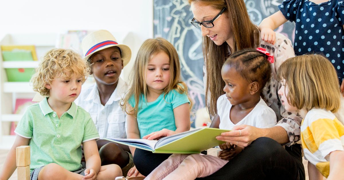 Preschool teacher reading a book to a group of children
