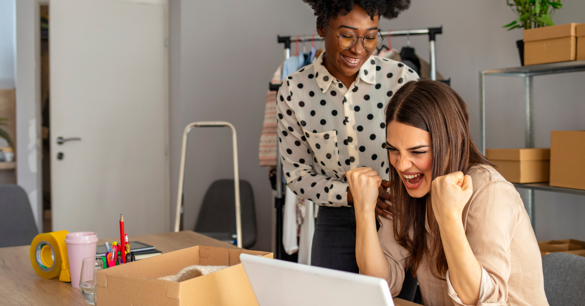 Two early childhood educators celebrating as they sit at a laptop
