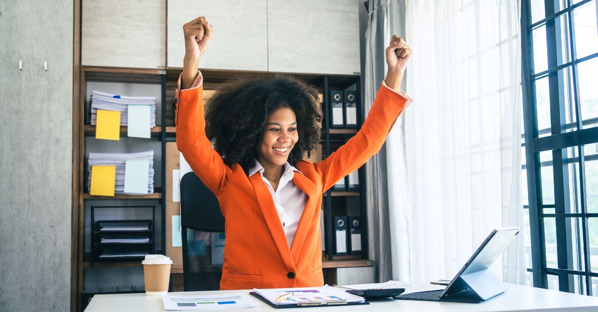 A new childcare owner sitting at their computer and celebrating as they accomplish steps to open their new center