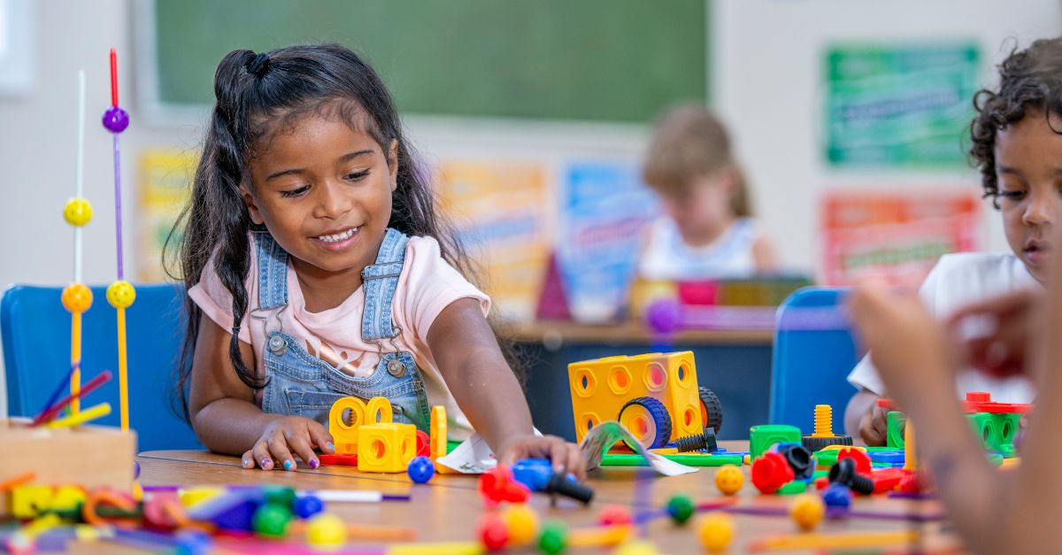Preschool girl playing with lego and pretend wheels and gears