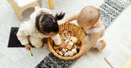 Two toddlers exploring the same bin of sensory materials 