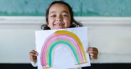 Preschooler holding up rainbow painting 