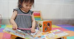 Toddler reading book on her own at school