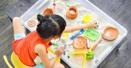 Preschool girl playing with a sand sensory bin