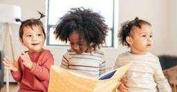 Three preschoolers reading a book together 