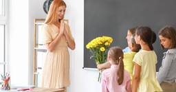 A group of kindergarten children bringing their teacher some yellow flowers
