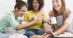 Group of early childhood educators sitting down together around a plate of cookies engaging in casual conversation during stress free break time 