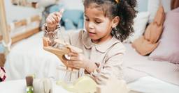 A young girl playing with a wooden helicopter in her preschool classroom.