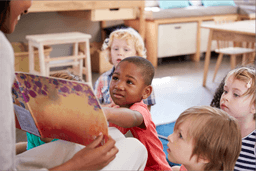A group of children interacting with a book during reading time