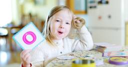 Preschooler holding up a card with the letter &quot;O&quot; as she practices saying &quot;O&quot; and building her letter recognition and phonemic awareness.