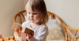 Toddler independently stacking wooden block tower
