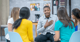 Early childhood leader has a hand on his chest while leading a reflection circle with a group of educators