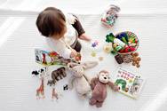 girl sitting among a variety of toys