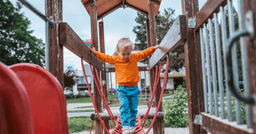 Toddler walking across a rope bridge  on the playground