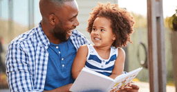 Dad reading to toddler outside
