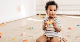 Toddler playing independently with blocks in sunny classroom
