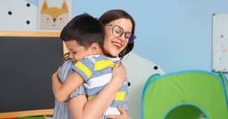 Teacher and preschooler hugging