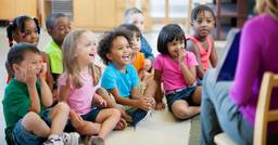 Toddlers sitting and watching their teacher show them curriculum content durning a lesson