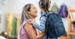 Parent picking up their preschooler from a childcare center and engaging in their learning.