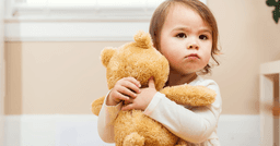 Toddler hugging her toy bear
