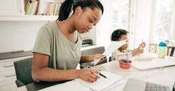 Mom sitting at kitchen island organizing tax forms with her toddler in the background 