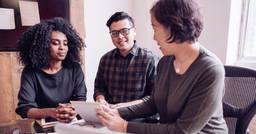 Preschool teacher sitting at desk and sharing at home learning resources with two parents