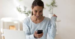 Mom smiling while looking at a childcare update of her child on her phone