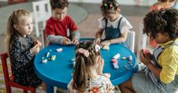 Children participating in a classroom activity overseen by educators who are taking classroom pics to share with families