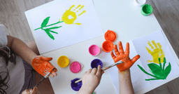 Preschoolers hands, being painted, and creating hand print flowers for mothers day. 