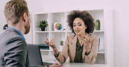 Childcare director sitting behind their desk discussing childcare policies with a father at the center.