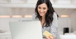 Parent smiling and holding credit card while they pay childcare tuition online