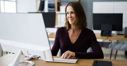 Childcare director smiling and sitting at computer 