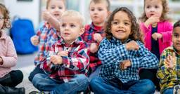 Group of preschoolers sitting on the carpet and singing songs during circle time