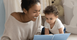 Mom and baby sitting on the floor and reading a book 