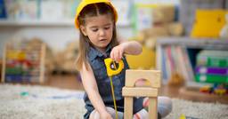 Preschool girl building with blocks and construction tools