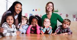 Early childhood educators looking happy as they take care of children and are supported enough to prevent burnout 