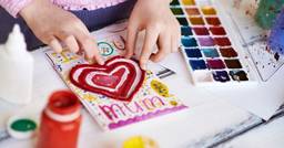 Preschooler making a valentines day card that says &quot;Mum&quot; while at school