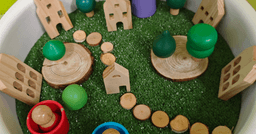 A sensory bin for a preschool classroom with green sand, green blocks and wooden play materials