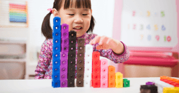 Preschool aged girl stacking blocks based on colour