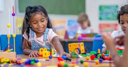 Preschool girl playing with lego and pretend wheels and gears