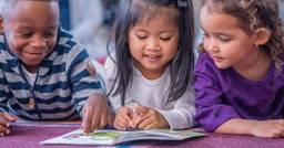 Three preschoolers reading a book together