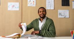 Preschool teacher smiling at camera while he organizes documentation for parent-teacher conferences
