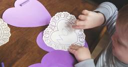 Toddler making a heart shaped card that says &quot;mom&quot; at daycare on valentines day