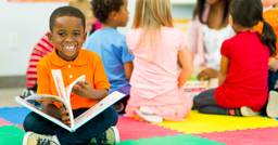 Preschool child is engaging in reading a book during free play time at daycare.