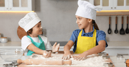 Two preschoolers working together to roll dough during cooking lesson.
