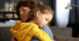 Preschool teacher hugging a young girl