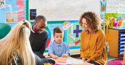 A family of 3 at a preschool parent teacher meeting