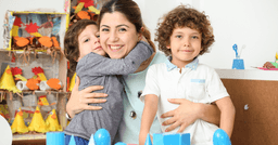 Preschool teacher smiling with two kids